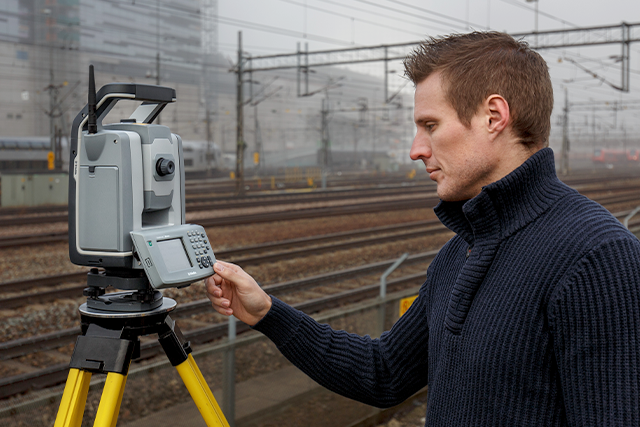 Male surveyor using Trimble S9 by rail tracks