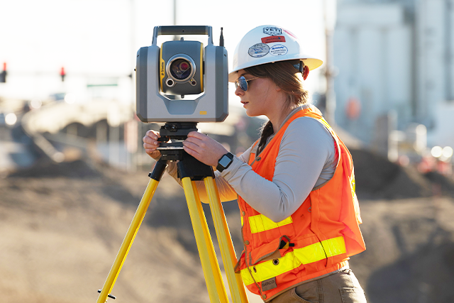 Female field surveyor using Trimble SX12 in construction site